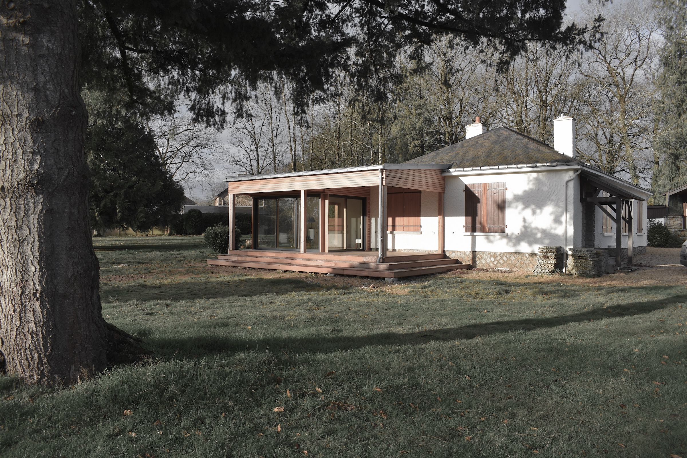 Extension en ossature bois largement vitrée, ouvrant l'existant sur le jardin