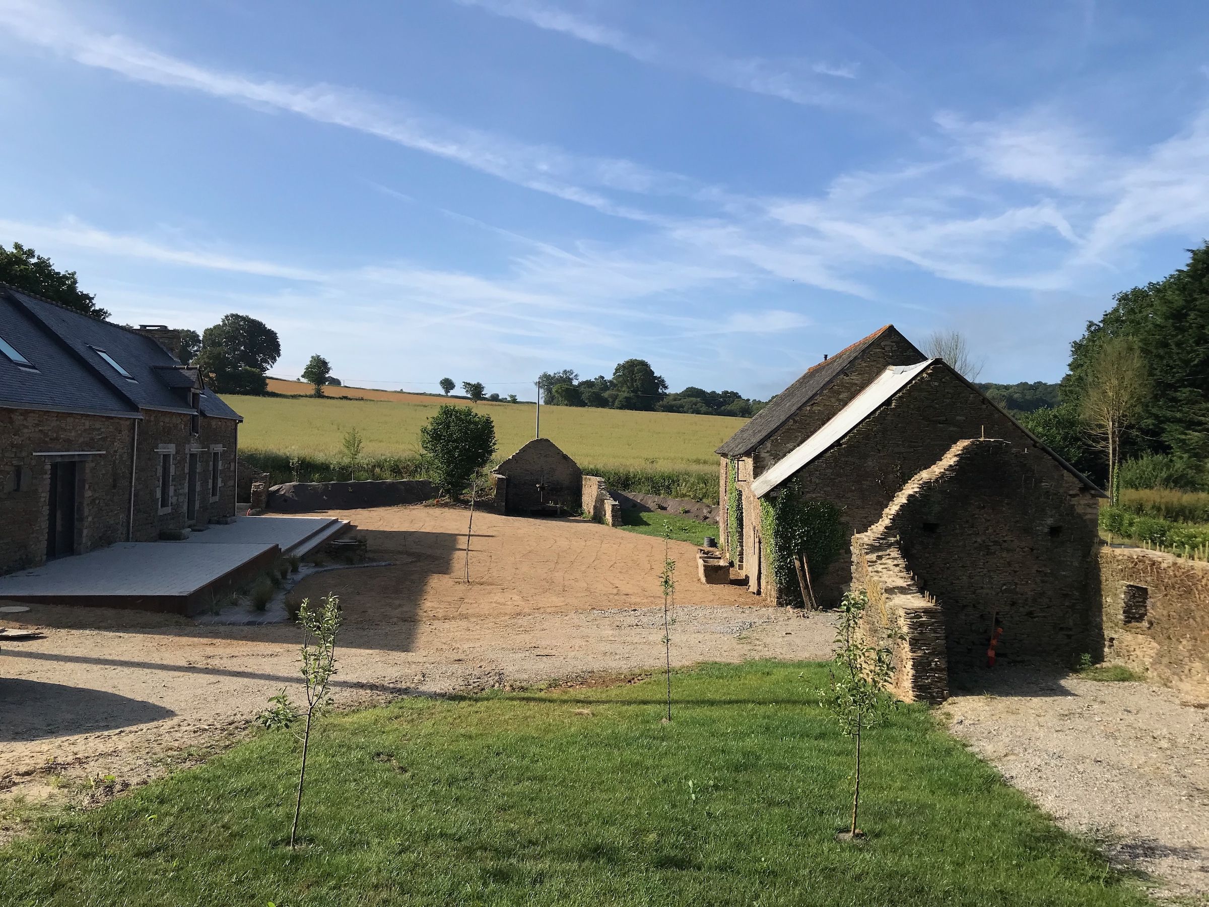 external view of the space between the main house and the guest accommodation (before grass seeding) showing the fields beyond