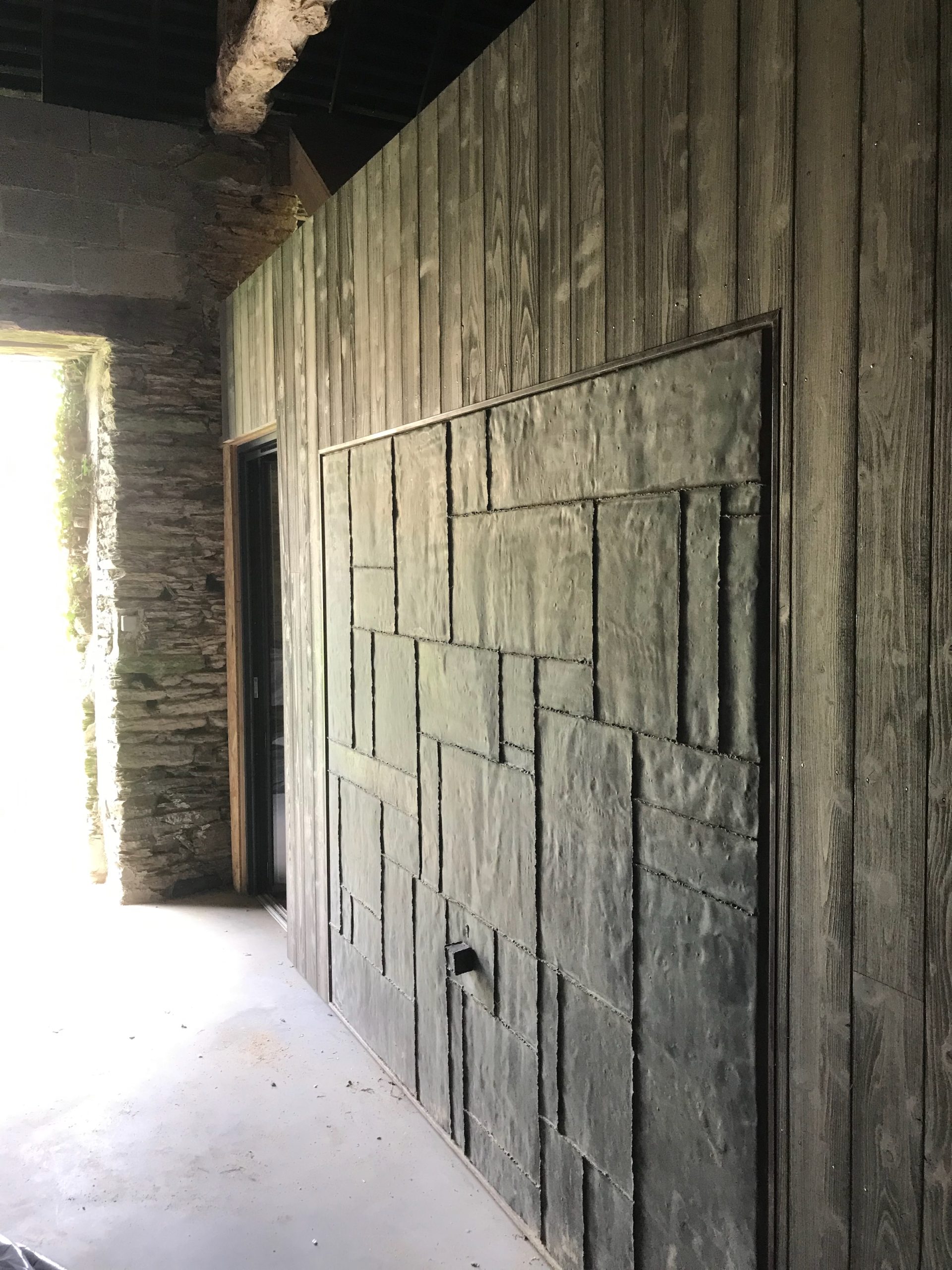 Inside the converted barn showing external elevation of the box with a box which forms the guest accommodation. Clad in Cypress and a reclaimed copper garage door