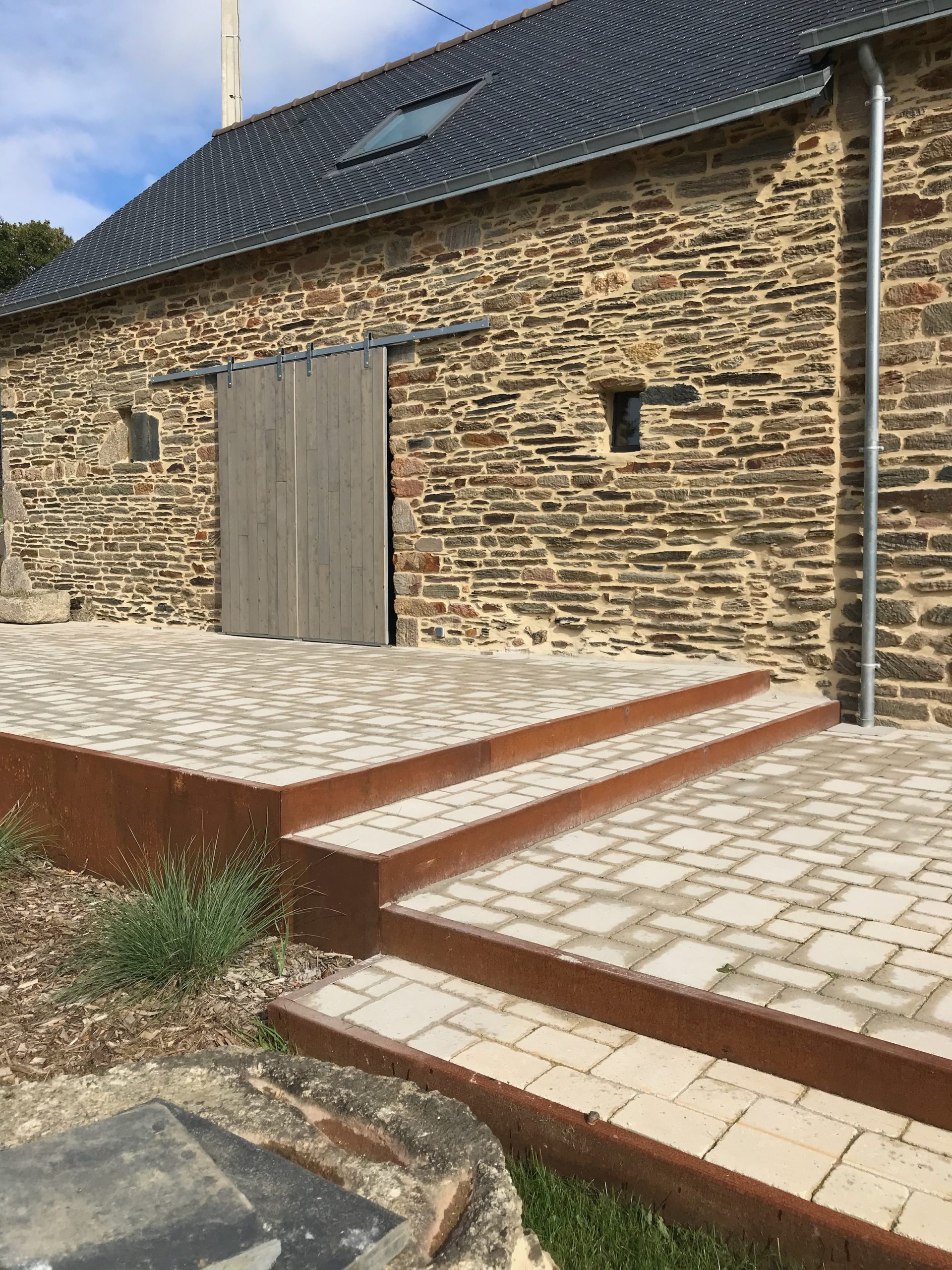 Les terrasses extérieures sont bordées d'acier Corten, complétant la pierre naturelle et les volets coulissants en cyprès