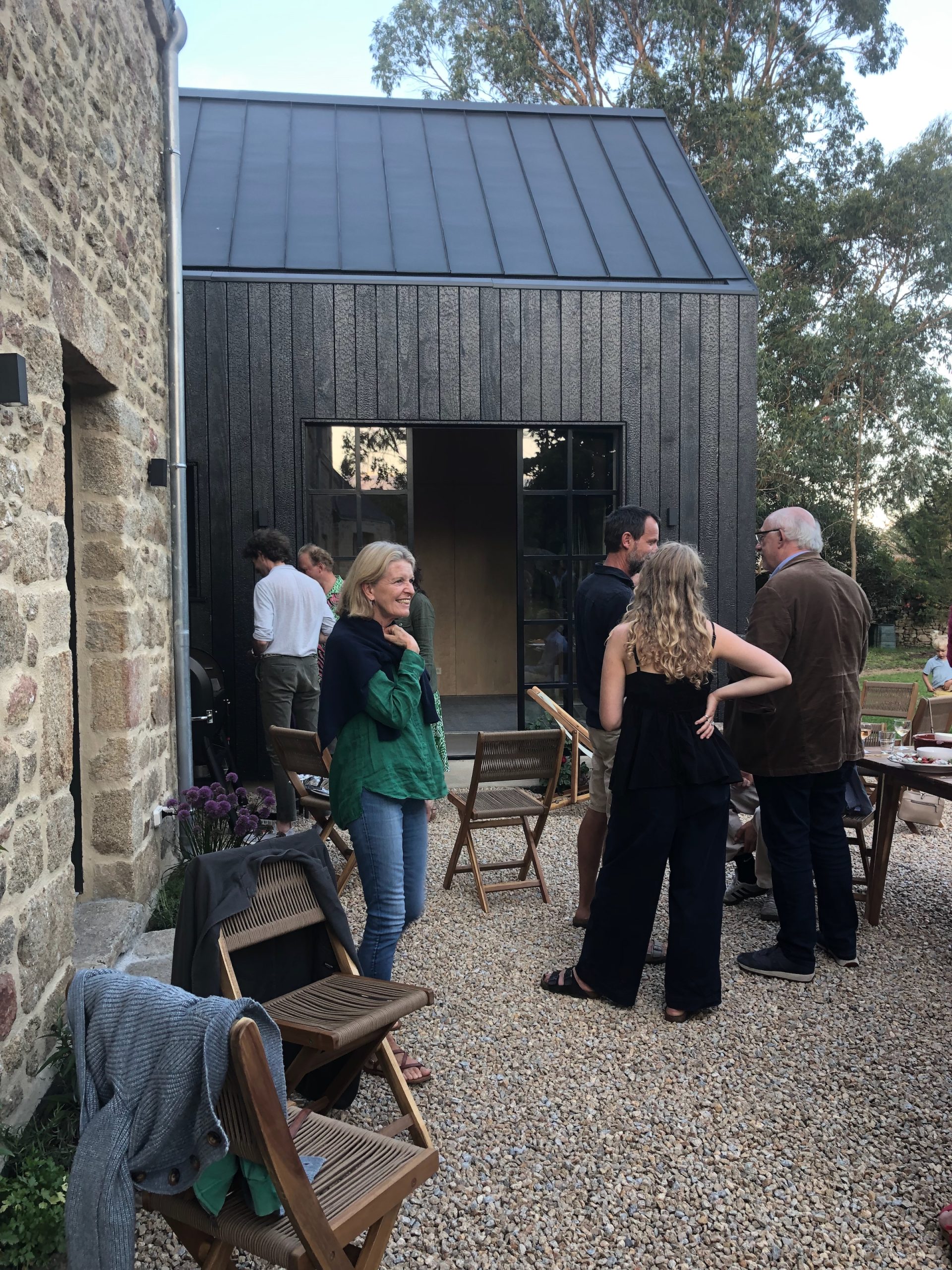 La terrasse extérieure fait le lien entre la longère rénovée et l'extension en bois brûlé