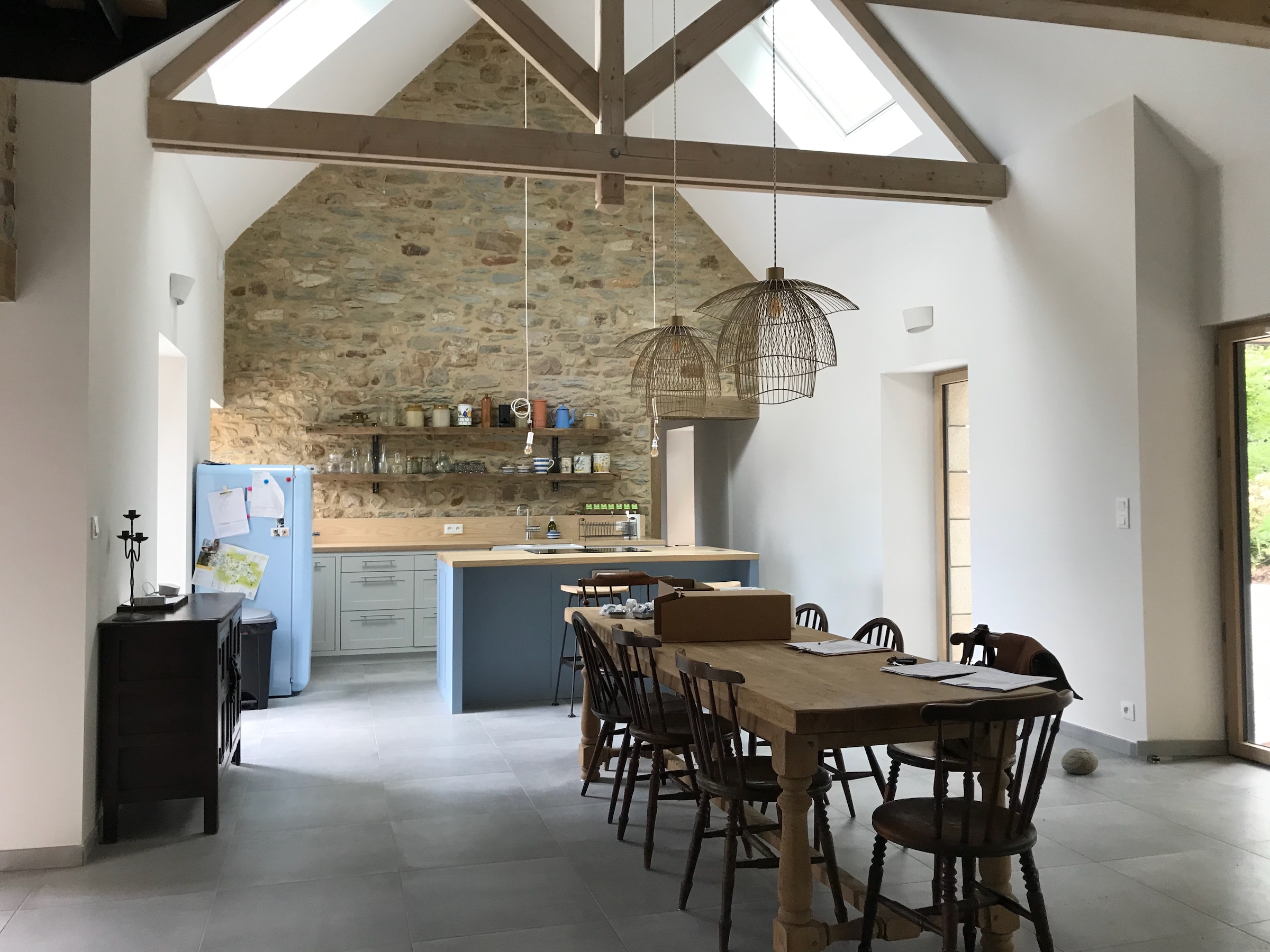 Espace de vie en double hauteur dans la grange rénovée avec mezzanine et escalier bois et acier