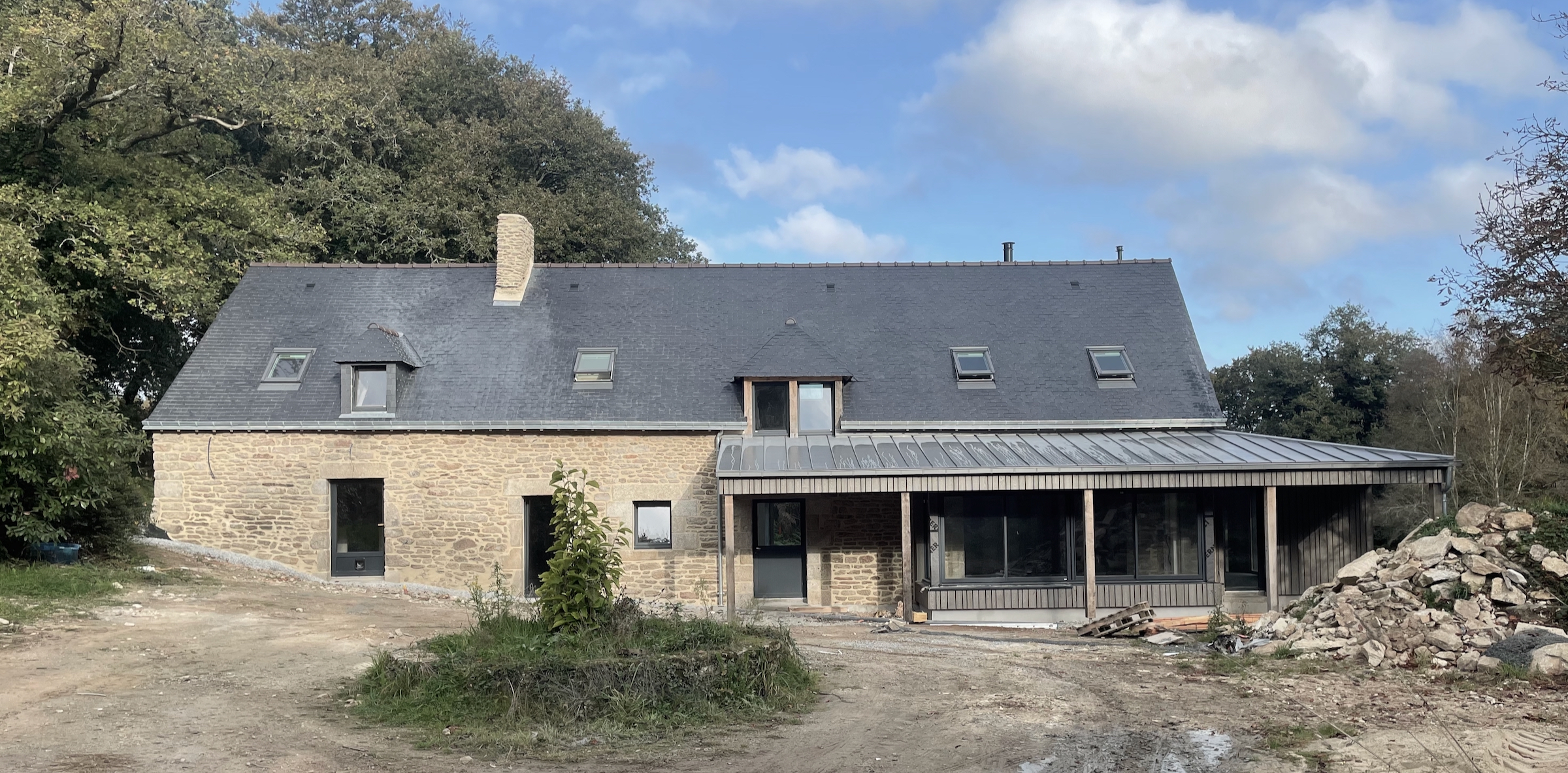 Le débord de toiture de l'extension crée une entrée et une terrasse couvertes, protégeant les larges baies vitrées du soleil estival